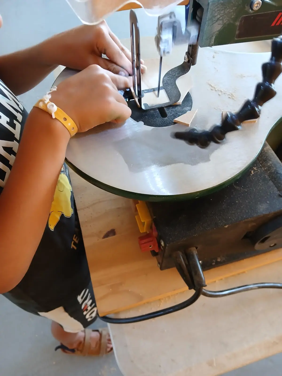 Enfant utilisant une scie à chantourner lors d'une animation scolaire