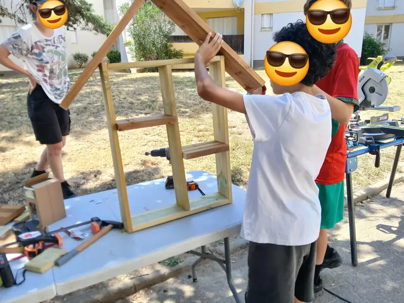 Enfants construisant une cabane en bois ensemble lors d'une animation scolaire